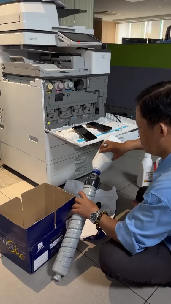 Kỹ thuật viên Chí Vinh thay mực máy photocopy màu Ricoh tại văn phòng, không tính thêm phí
